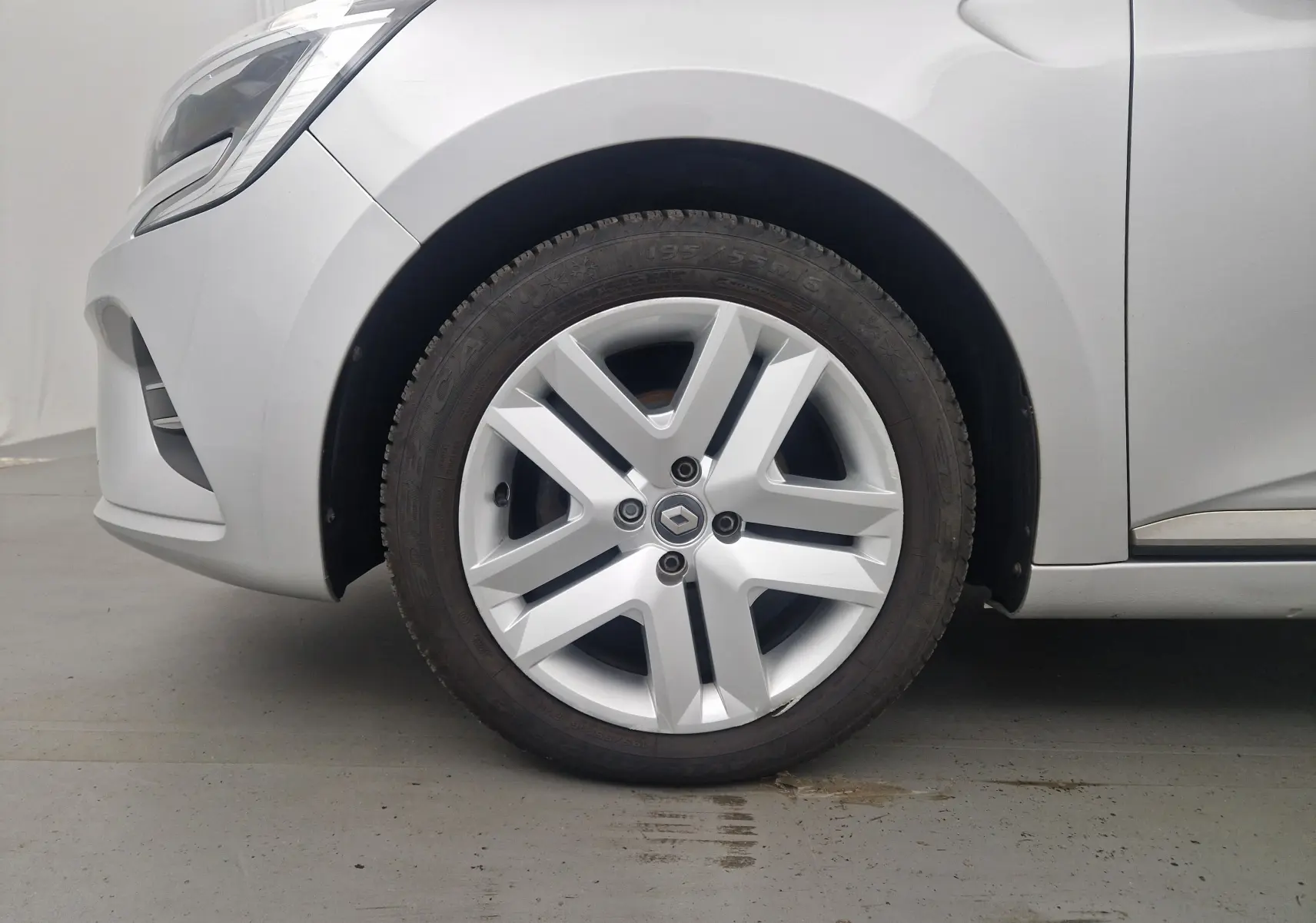 Gros plan sur la roue avant gauche d'une Renault Clio V gris platine, avec jante en alliage au design moderne.