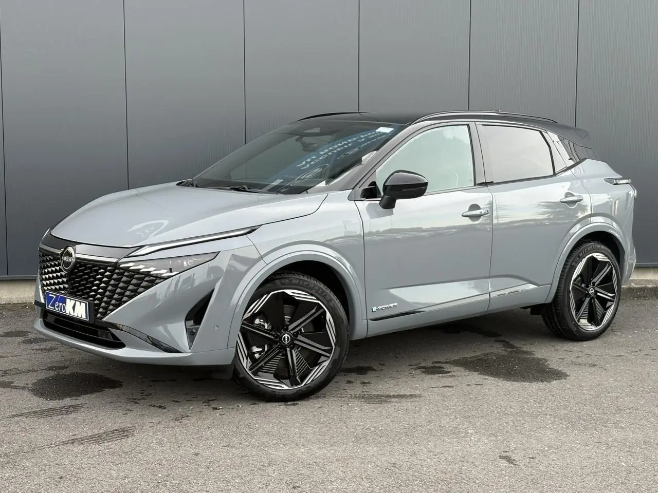 Nissan Qashqai 2025 gris Ceramic en 3/4 avant droit avec toit noir panoramique et jantes alliage noires.