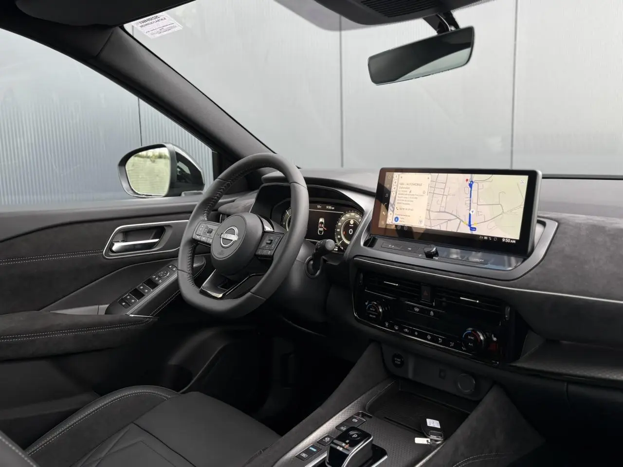 Intérieur du Nissan Qashqai 2025 vu côté conducteur, tableau de bord noir avec écran tactile GPS et volant cuir.