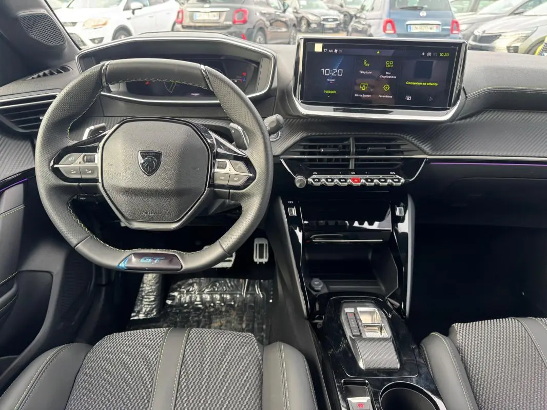 Vue intérieure avant du Peugeot 208 Hybrid 110 e-DCS6 GT gris, volant compact, écran tactile et console centrale moderne.