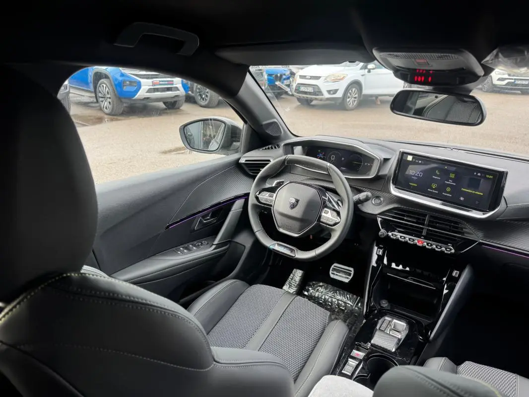 Vue intérieure avant droite du Peugeot 208 Hybrid 110 e-DCS6 GT gris, avec volant compact et écran tactile central.
