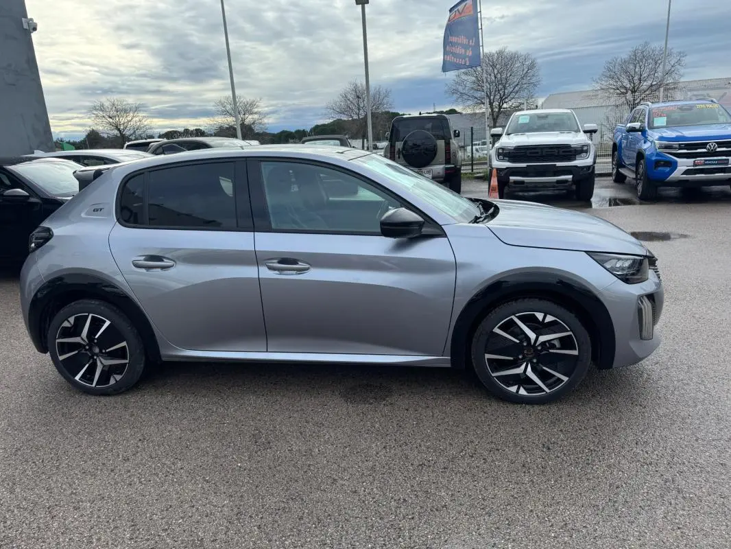 Profil droit d'une Peugeot 208 Hybrid 110 GT gris avec jantes alliage 17 pouces et vitres teintées.