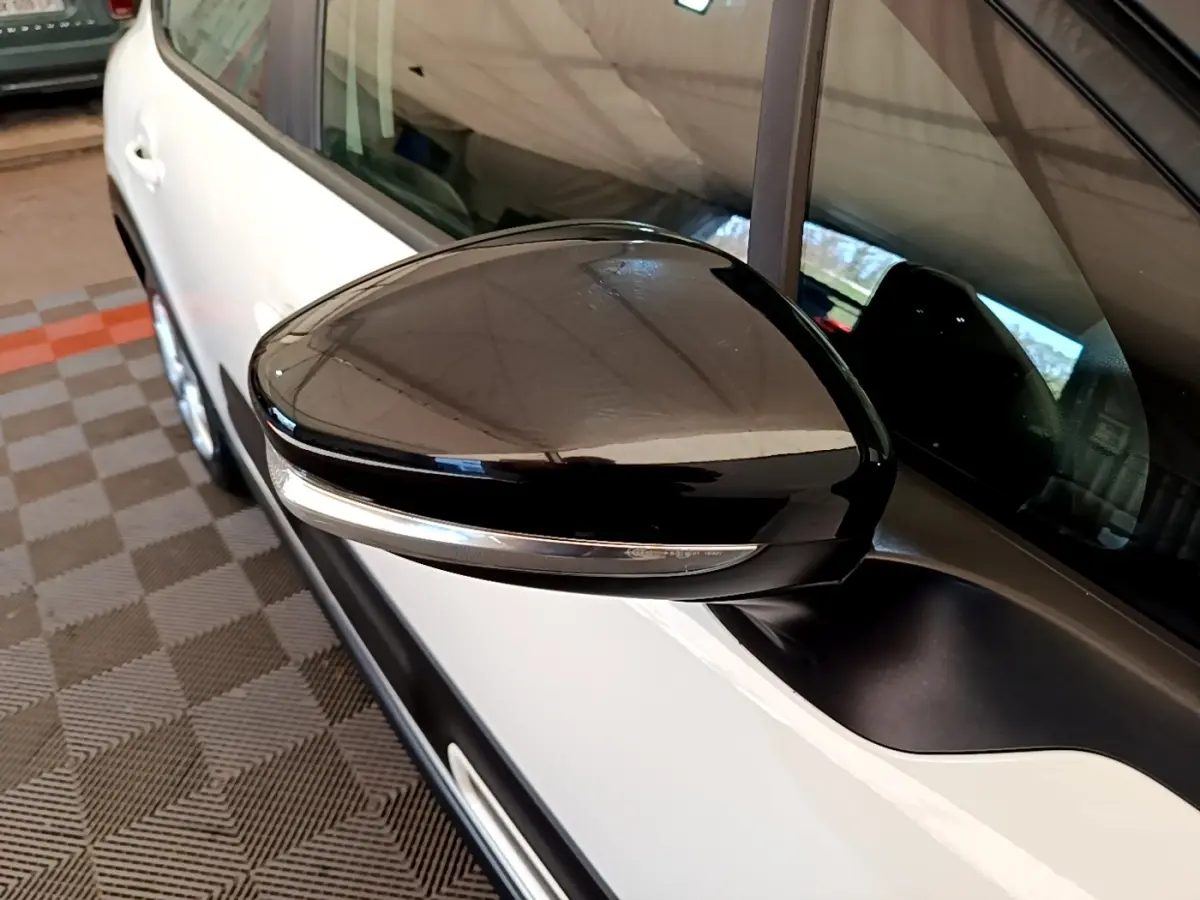 Rétroviseur noir avec clignotant intégré côté gauche d'une Citroën C3 blanche vue de profil rapproché.