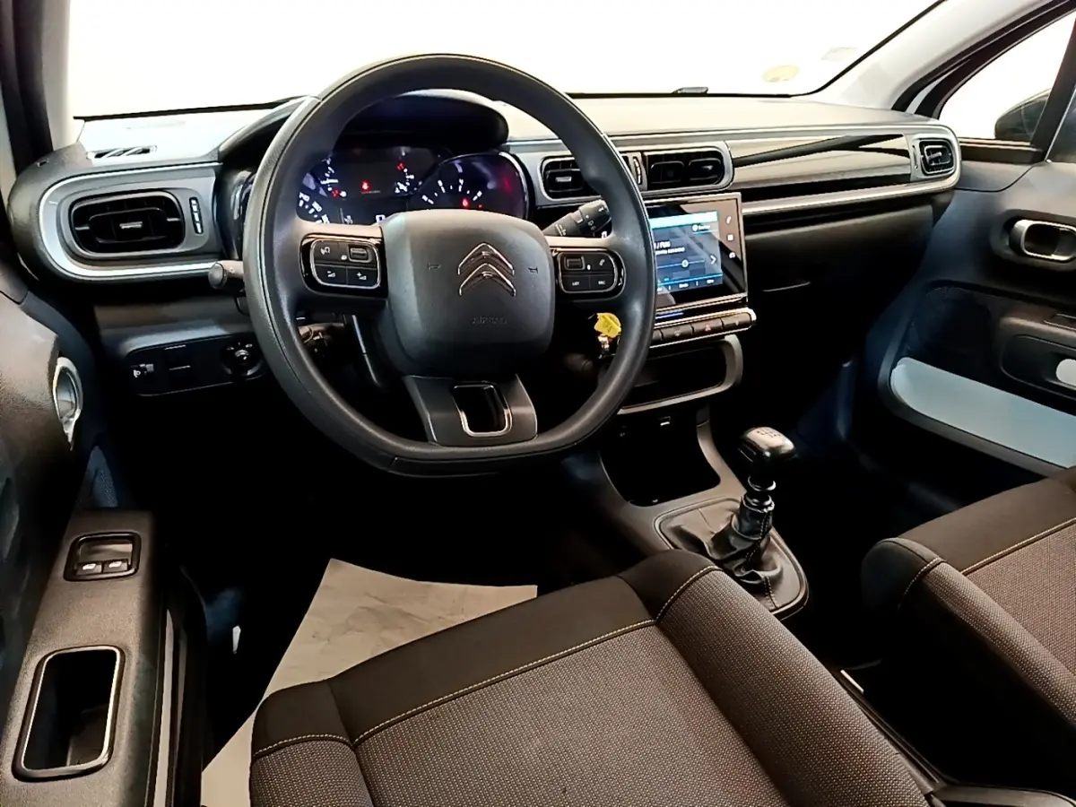 Vue intérieure avant de la Citroën C3 2022 avec volant multifonctions, tableau de bord noir et levier de vitesse manuel.