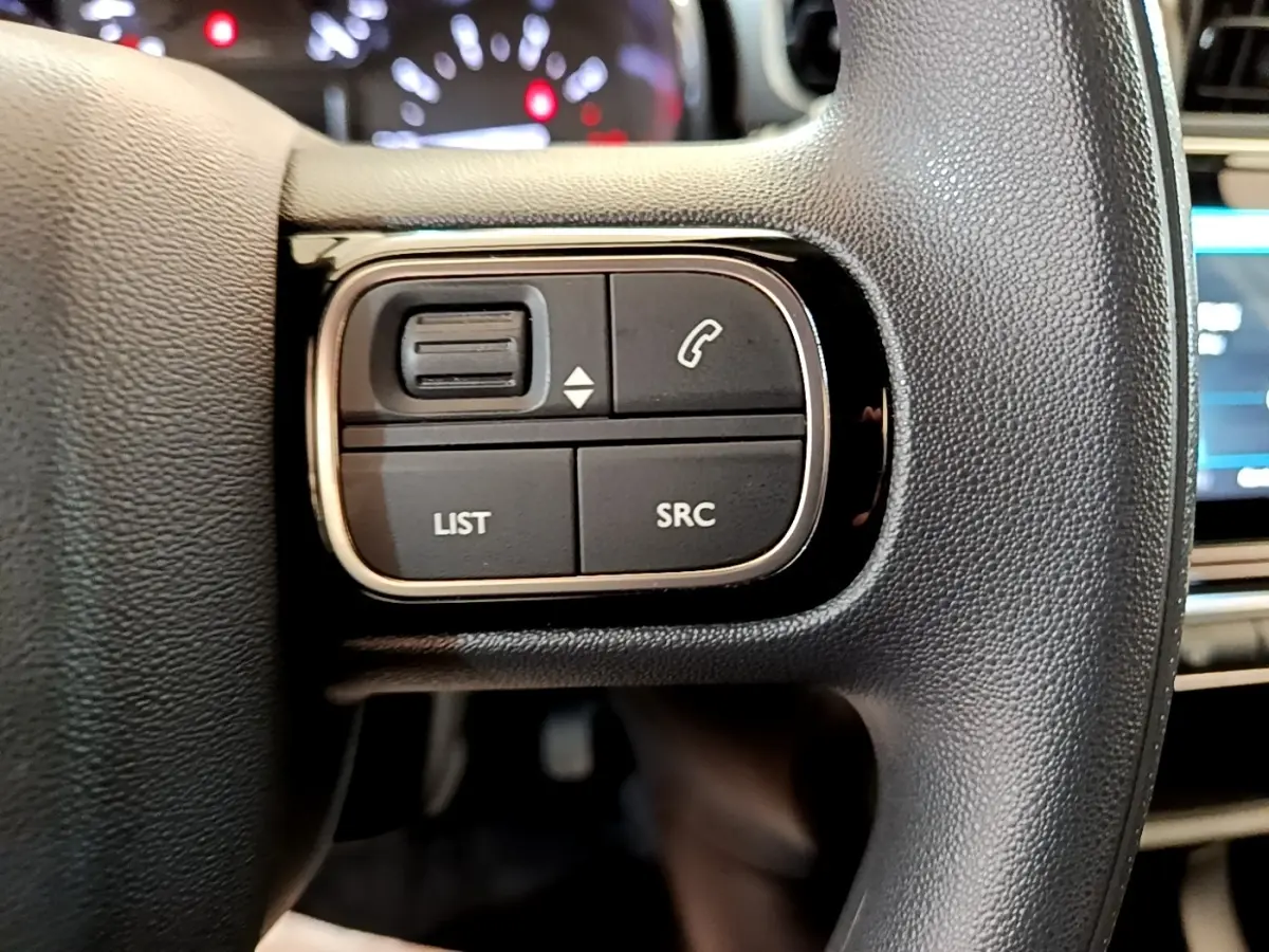 Gros plan sur les commandes gauche du volant noir de la Citroën C3 2022 avec boutons LIST, SRC et téléphone.