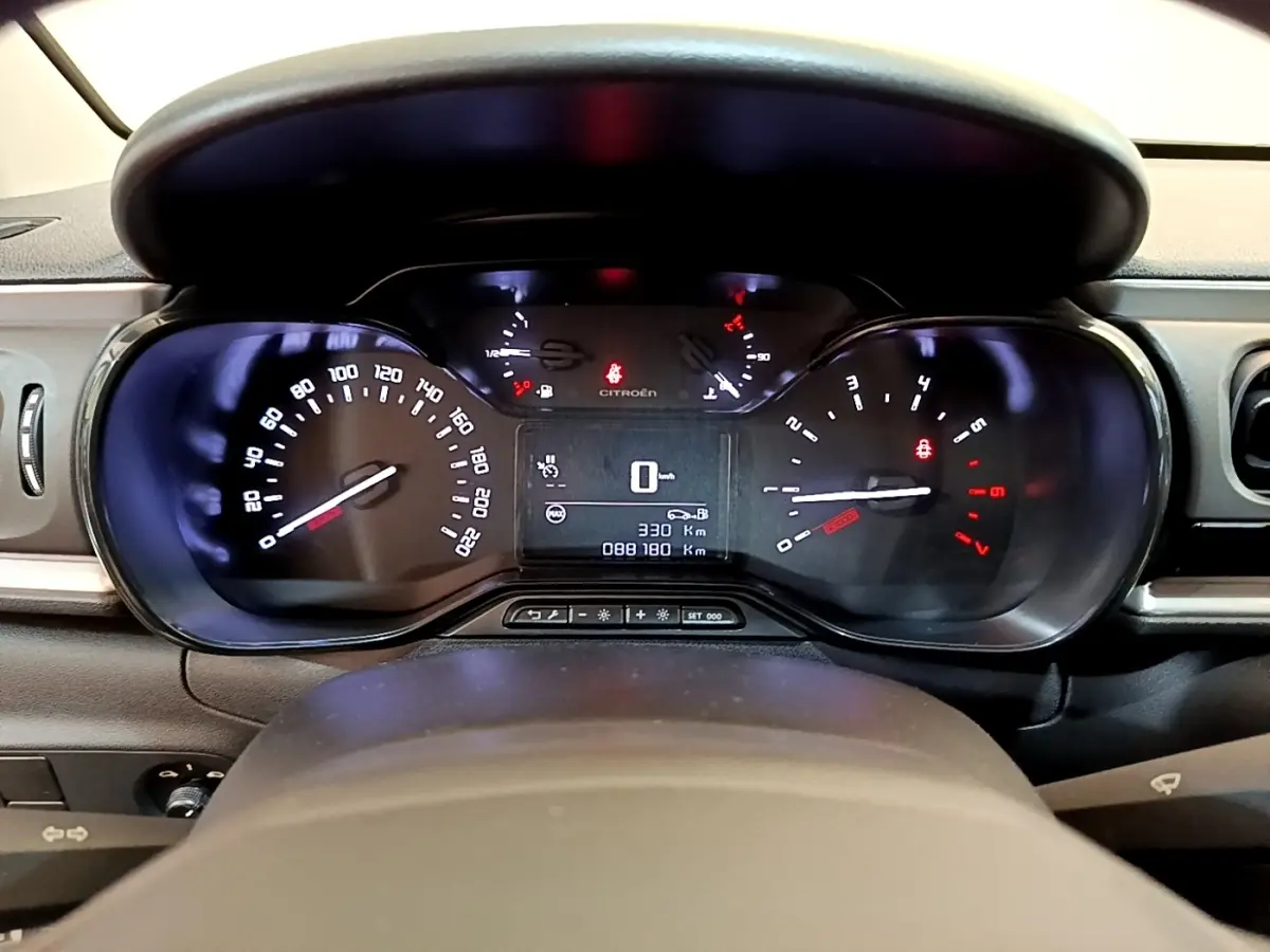 Vue rapprochée du tableau de bord de la Citroën C3 blanche, affichant le compteur et l'ordinateur de bord digital.