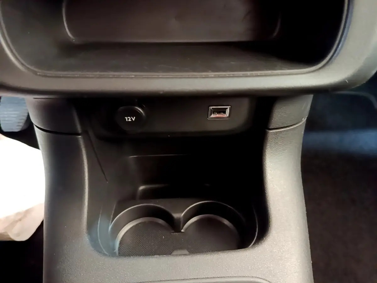 Gros plan sur la console centrale noire de la Citroën C3 avec prise 12V et port USB visible.