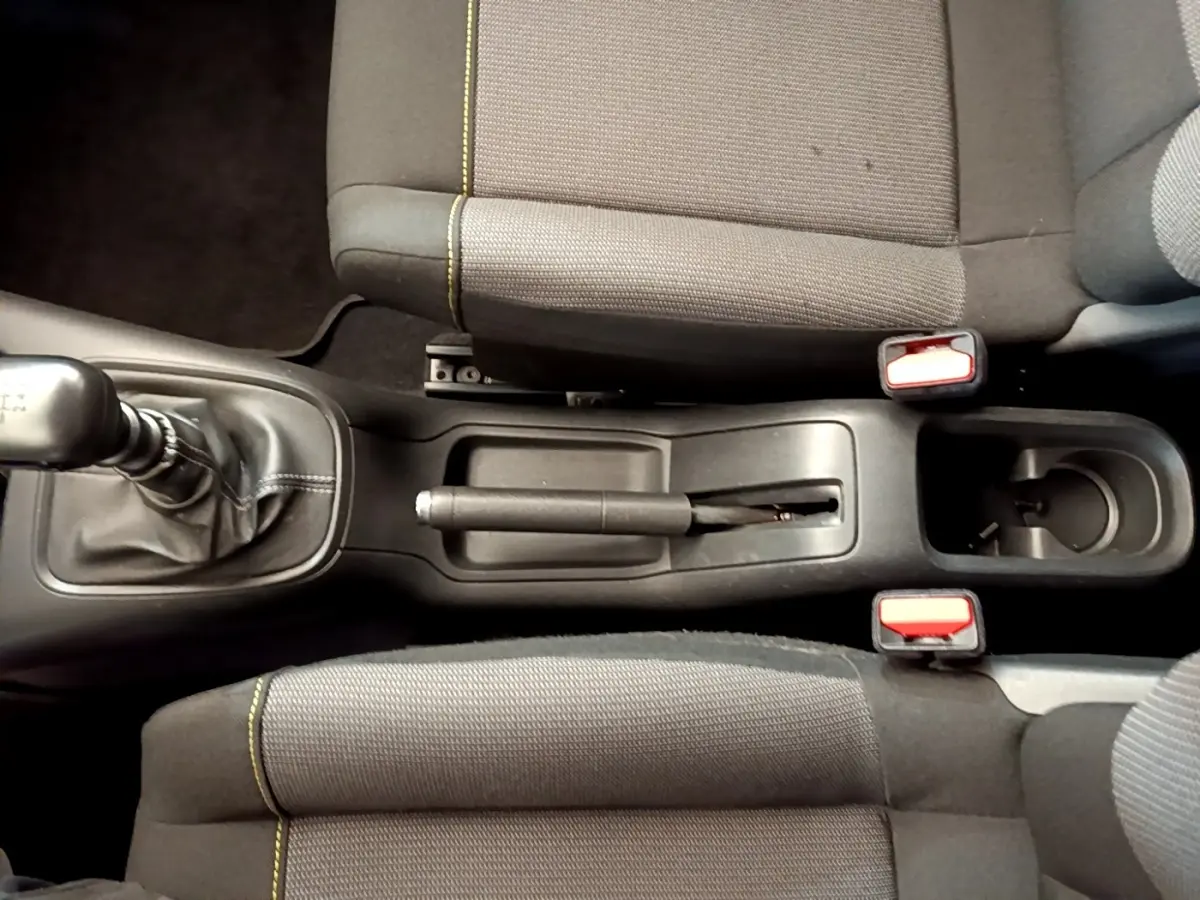 Vue plongeante sur la console centrale de la Citroën C3 avec levier de vitesse manuel et sièges tissu gris à surpiqûres jaunes.