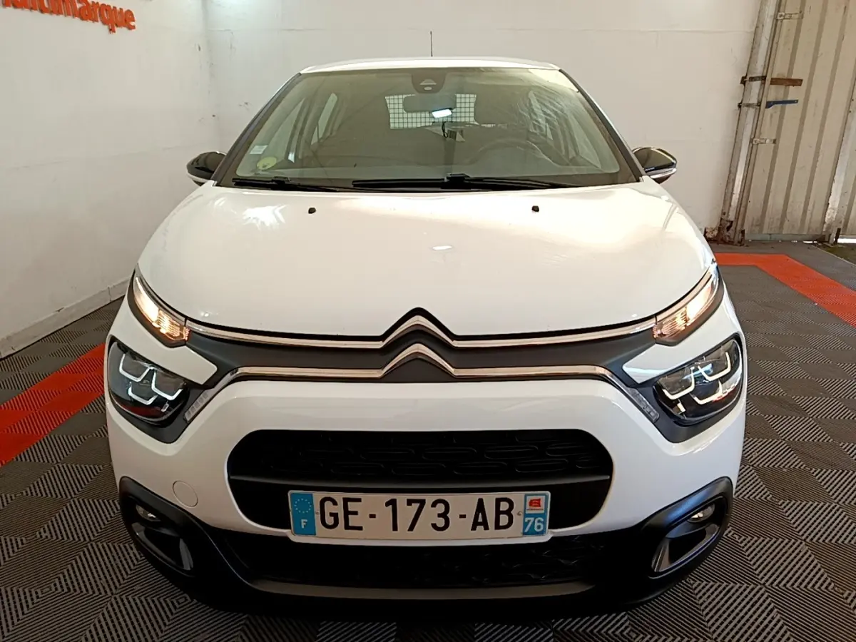 Vue avant d'une Citroën C3 blanche 2022 avec phares LED et calandre noire dans un garage.