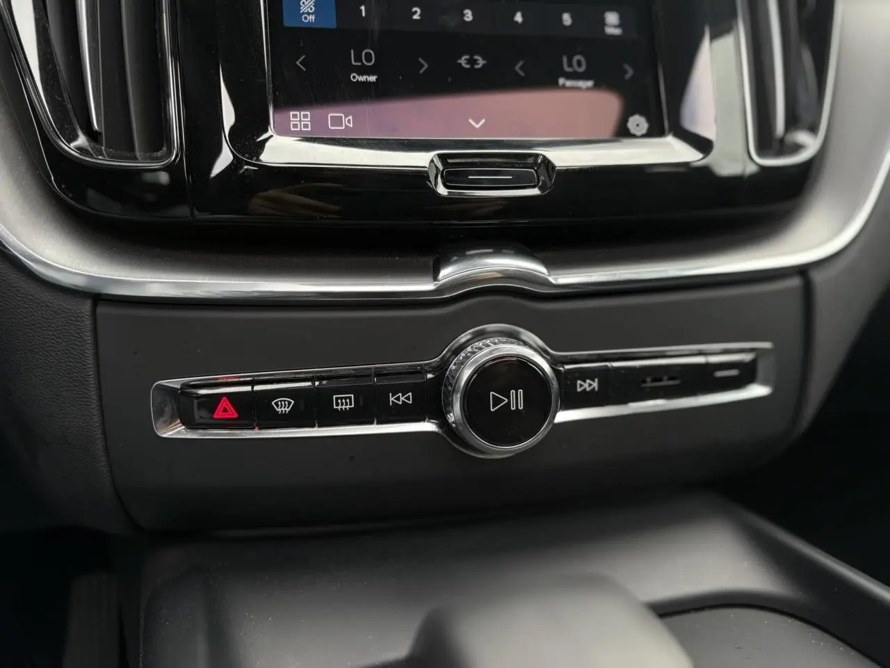 Gros plan sur la console centrale du Volvo XC60 2024, avec commandes multimédia et finition noire brillante.