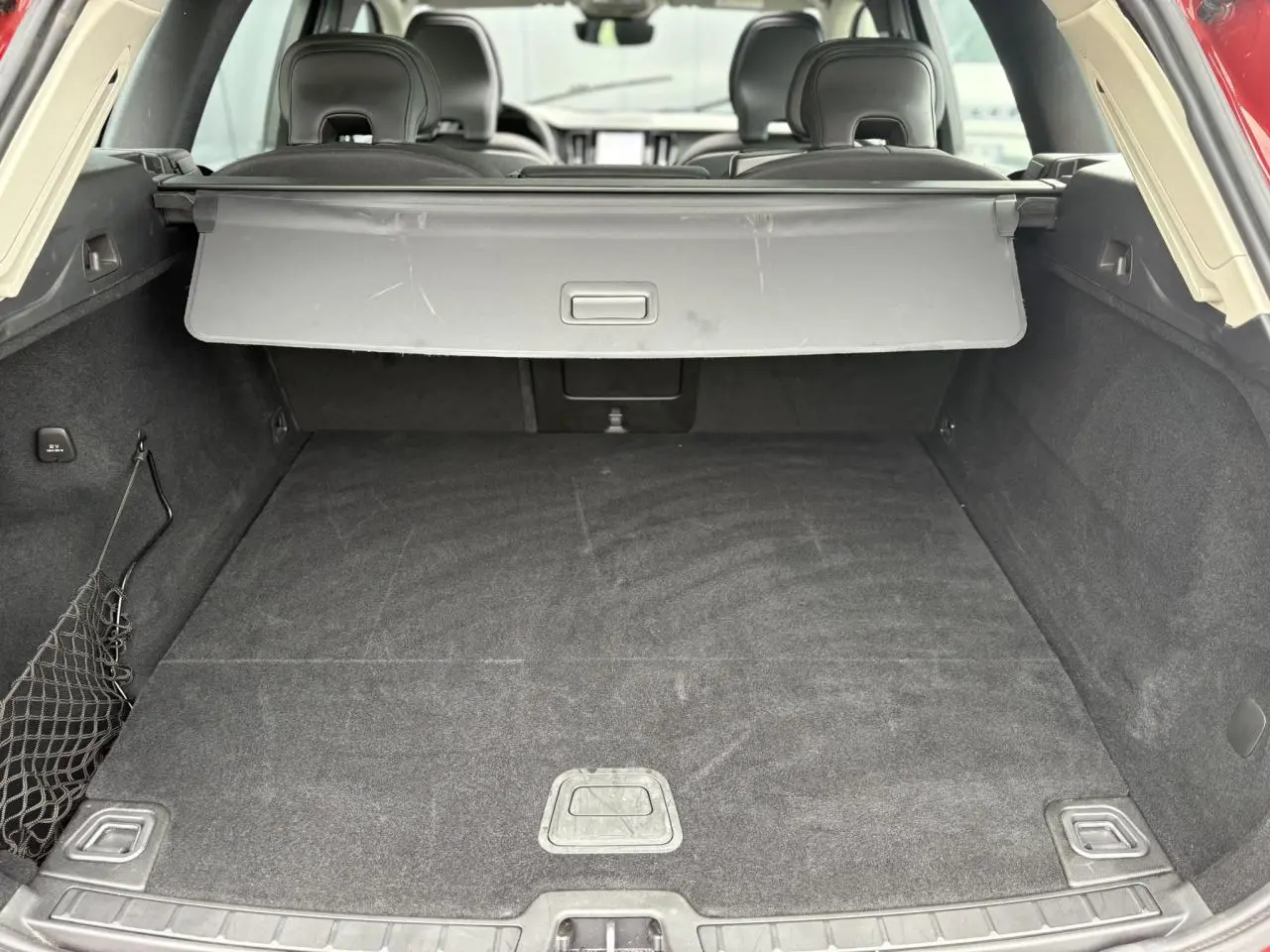 Coffre ouvert vu de l'arrière d'un Volvo XC60 rouge Fusion, avec cache-bagages et intérieur noir.