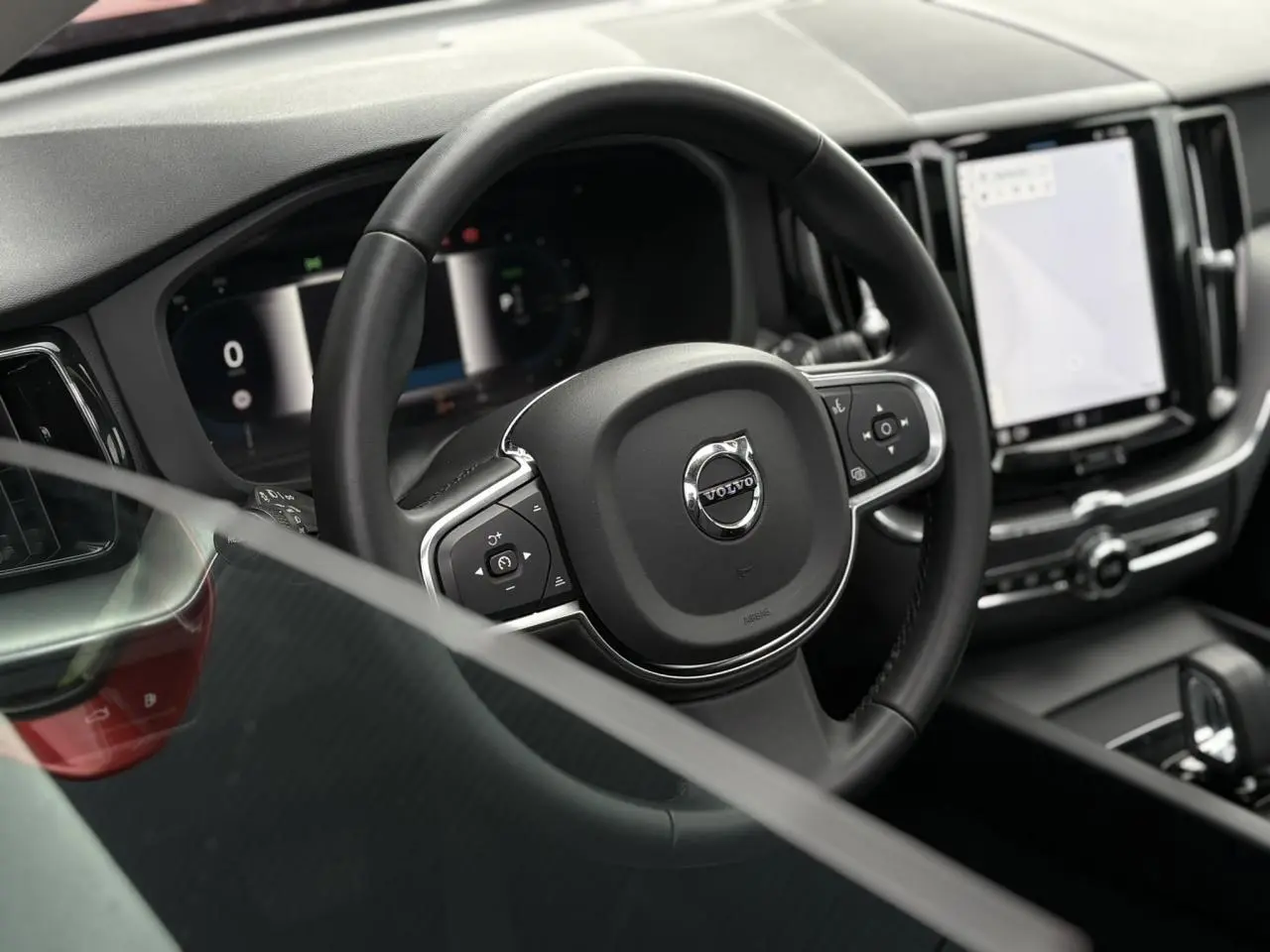 Vue rapprochée du volant noir et du tableau de bord digital du Volvo XC60 T6 AWD PHEV 2024.