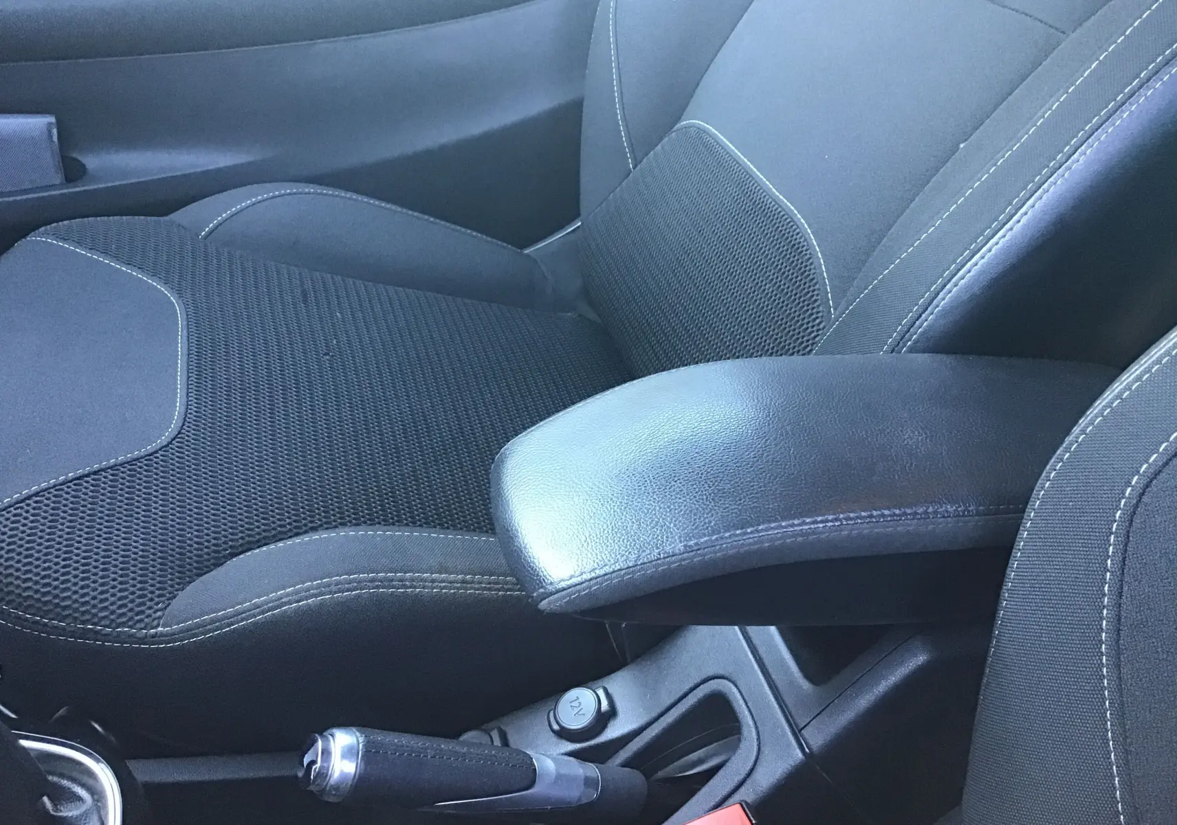 Détail de l'intérieur montrant le siège avant droit noir avec accoudoir cuir et frein à main sur Citroën DS3 gris clair.