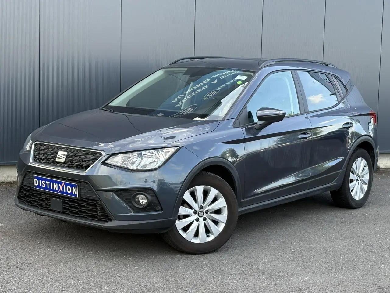 SEAT Arona gris magnétique en 3/4 avant droit, avec jantes alliage et calandre noire distinctive.