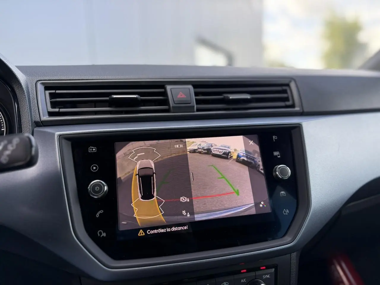 Écran tactile central affichant la caméra de recul et l'aide au stationnement du SEAT Arona gris magnétique, vue intérieure.