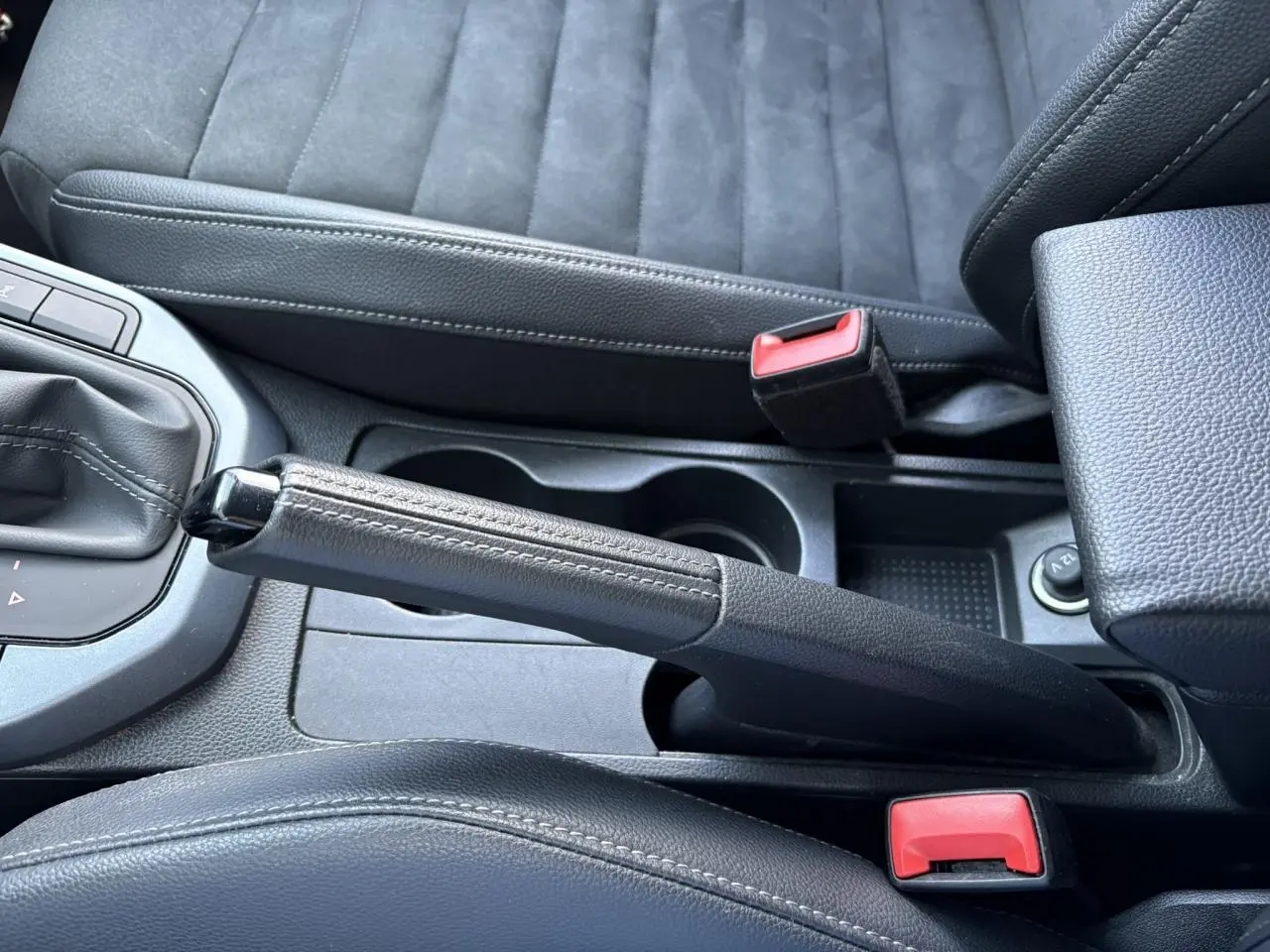 Vue rapprochée de la console centrale du SEAT Arona 2020, montrant frein à main cuir et sièges suédine gris.