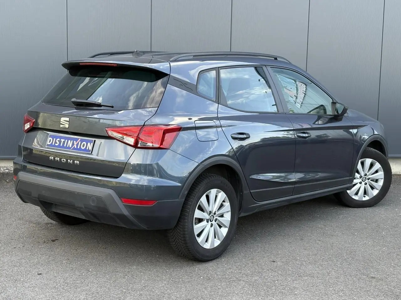 SEAT Arona TSI 110 DSG Style gris magnétique vu en 3/4 arrière droit, vitres teintées et jantes alliage visibles.
