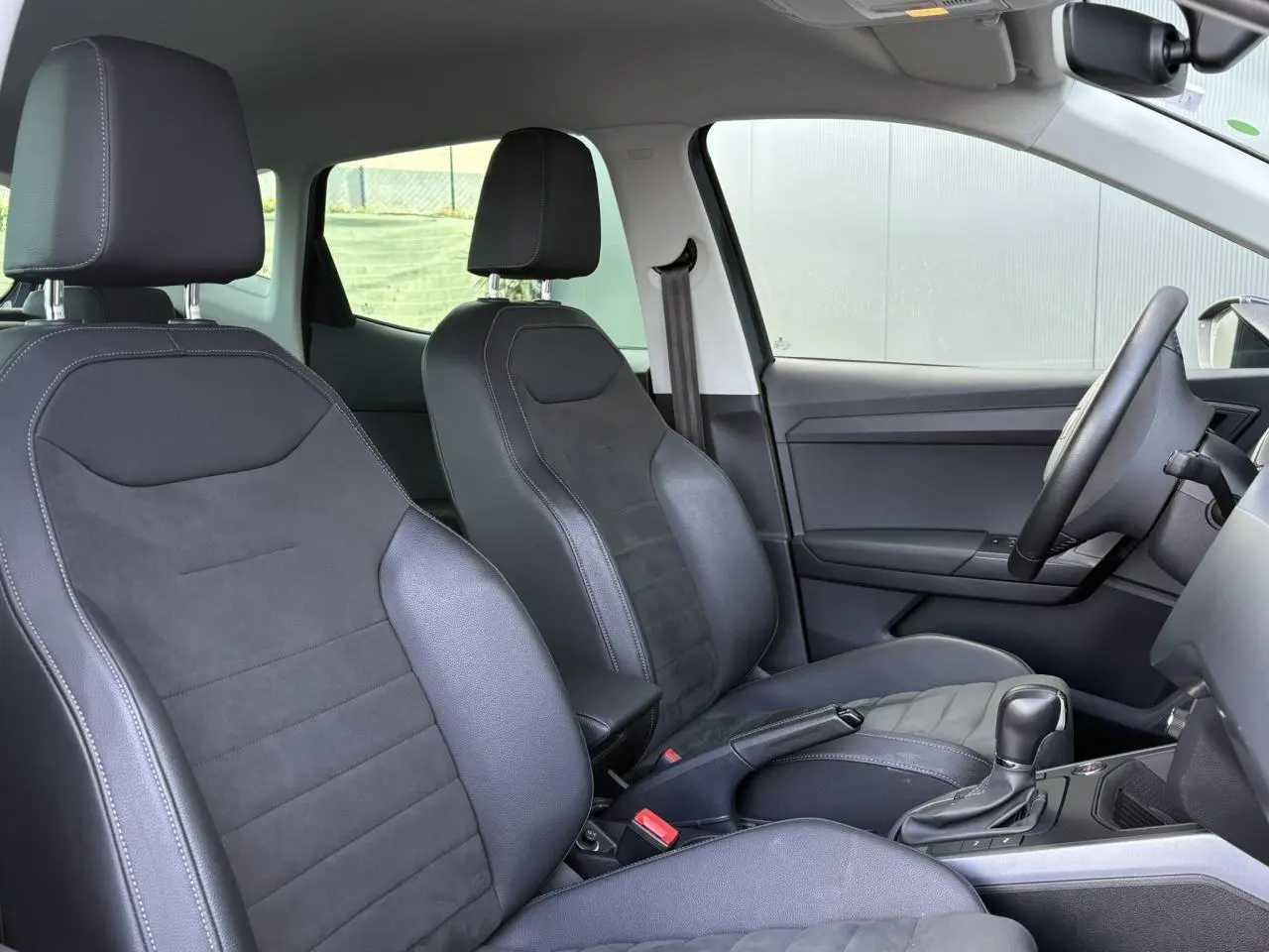 Vue intérieure côté conducteur du SEAT Arona 2020, sièges en suédine gris foncé avec console centrale et levier de vitesse automatique.