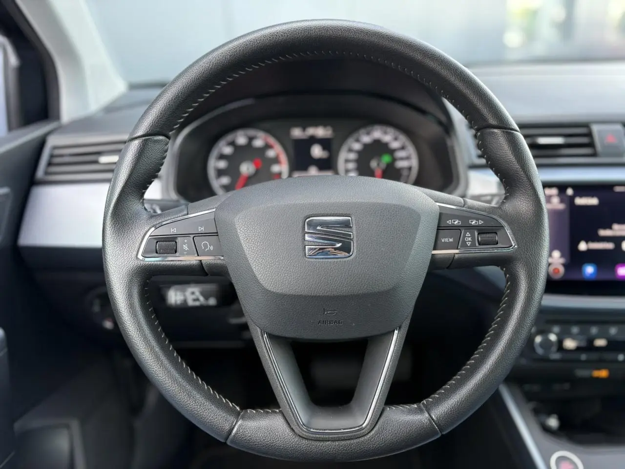 Volant en cuir noir de la SEAT Arona TSI 110 DSG Style 2020, avec commandes multifonctions et tableau de bord visible.