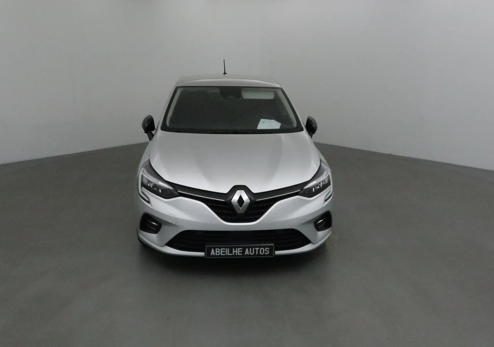 Renault Clio V gris platine vue de face, mettant en valeur la calandre noire et les phares LED modernes.