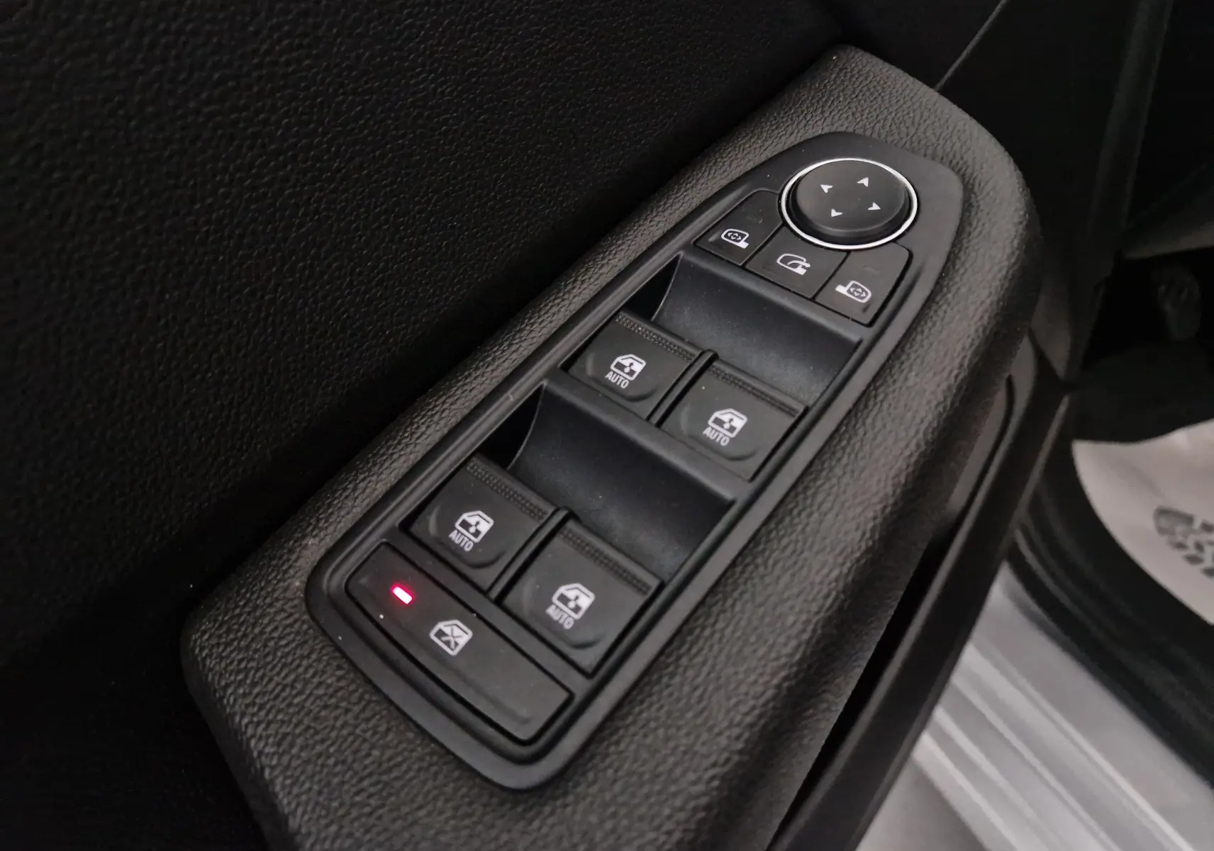 Gros plan sur les commandes de lève-vitres et rétroviseurs côté conducteur d'une Renault Clio V gris platine 2021.