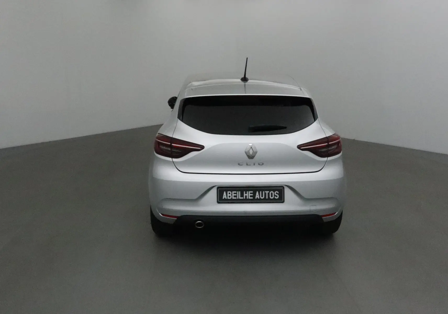 Vue arrière d'une Renault Clio V gris platine 2021 avec vitres teintées et plaque Abeilhe Autos visible.