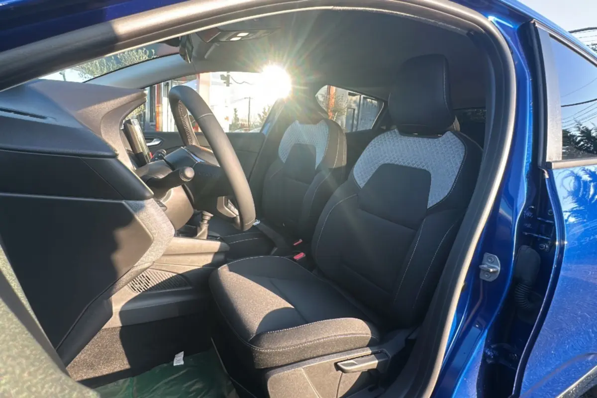 Intérieur avant droit d'une Renault Clio DCI 100 Evolution Camera 2025 bleu iron, sièges tissu noir et gris clair.