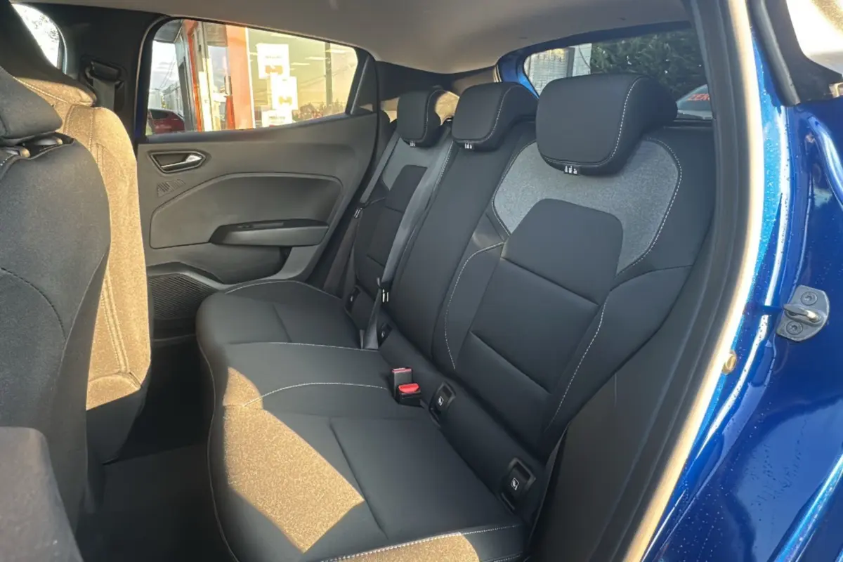 Vue intérieure arrière côté droit de la Renault Clio 2025 bleu iron, montrant les sièges arrière en tissu noir avec surpiqûres blanches.