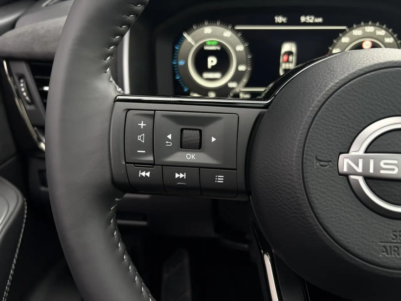 Gros plan sur le volant cuir noir du Nissan Qashqai 2025 avec commandes intégrées et tableau de bord numérique.