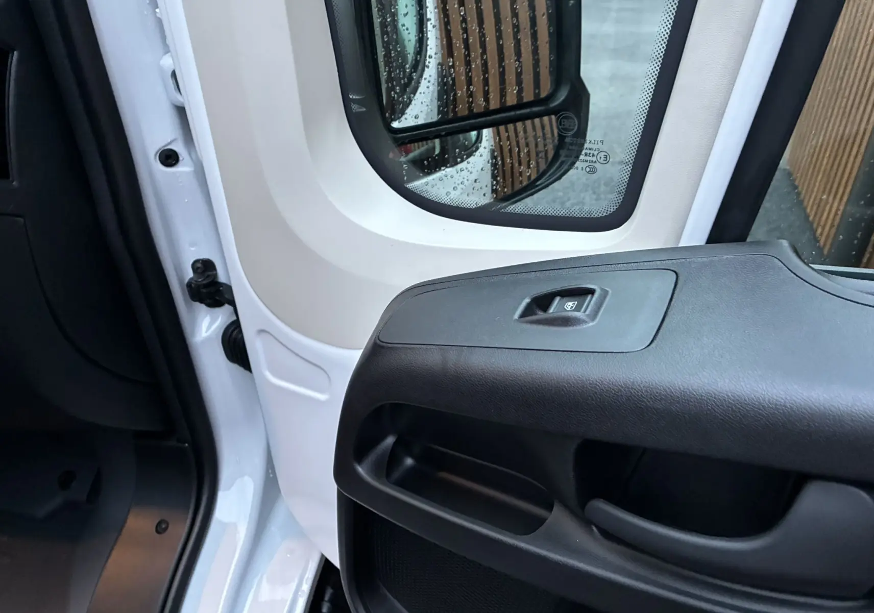 Vue rapprochée de la portière avant gauche blanche du Fiat Ducato Fourgon 2025, avec commande de vitre électrique.