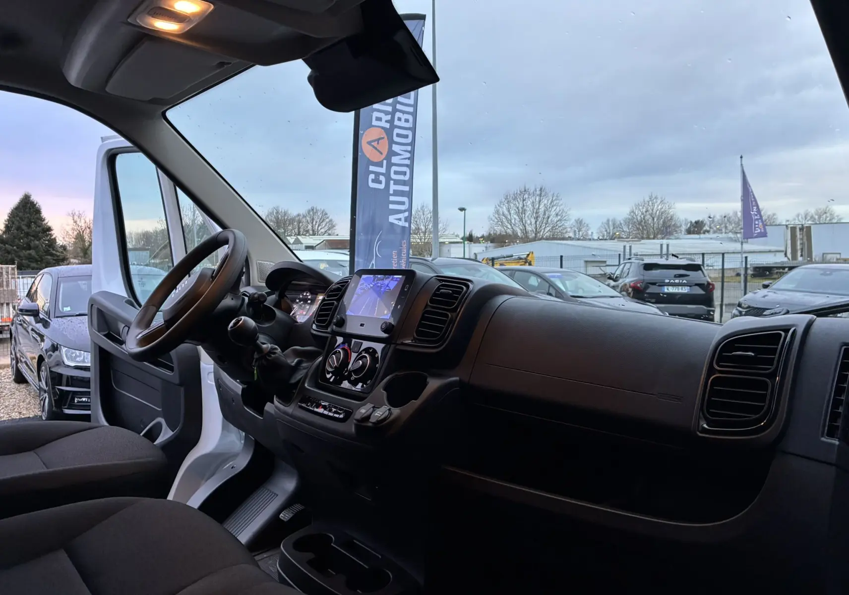 Vue intérieure côté conducteur du Fiat Ducato Fourgon blanc 2025, mettant en valeur le tableau de bord et l'écran tactile.