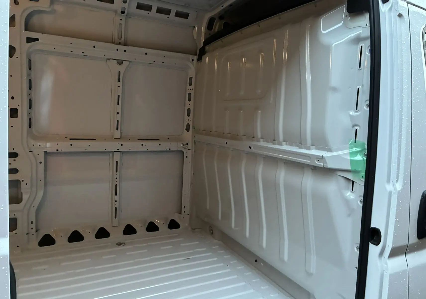 Vue intérieure arrière du fourgon blanc FIAT Ducato 2.2 140 L2H2 2025, montrant la zone de chargement vide et métallique.