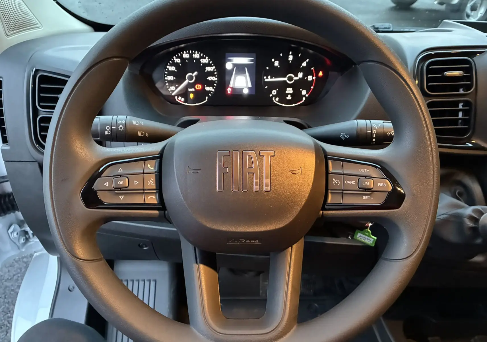 Vue rapprochée du volant noir du Fiat Ducato Fourgon 2025 avec commandes intégrées et tableau de bord numérique allumé.