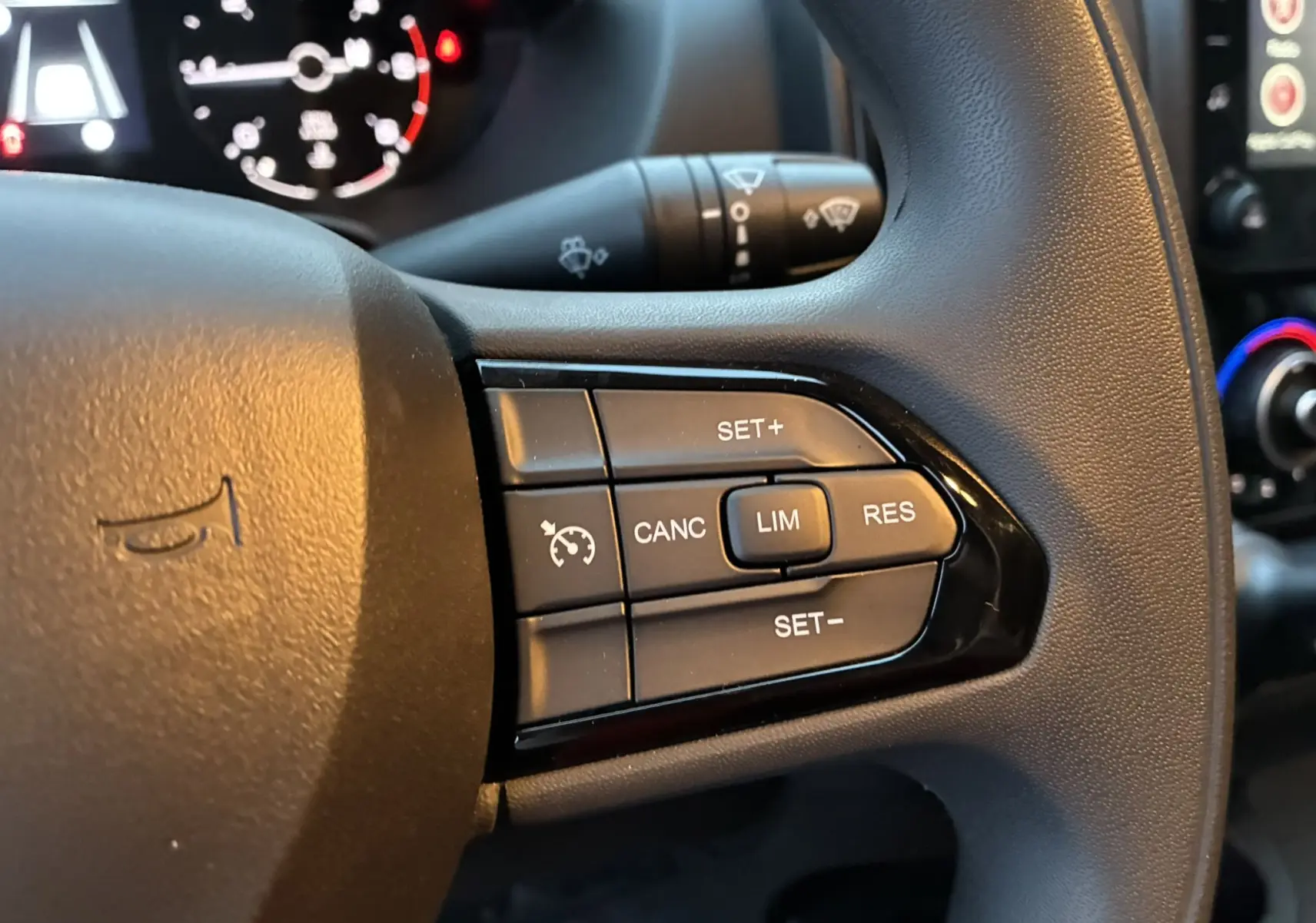 Gros plan sur les commandes de régulateur de vitesse au volant noir du Fiat Ducato Fourgon blanc 2025.