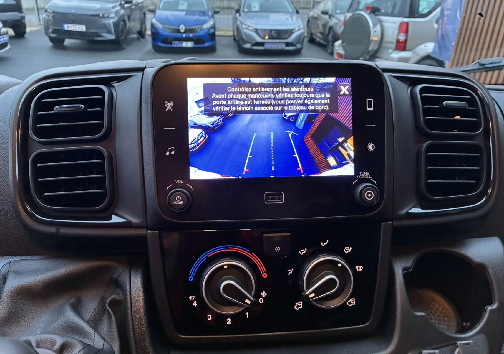 Vue intérieure du tableau de bord du Fiat Ducato Fourgon blanc 2025, avec écran de caméra de recul et commandes de climatisation.