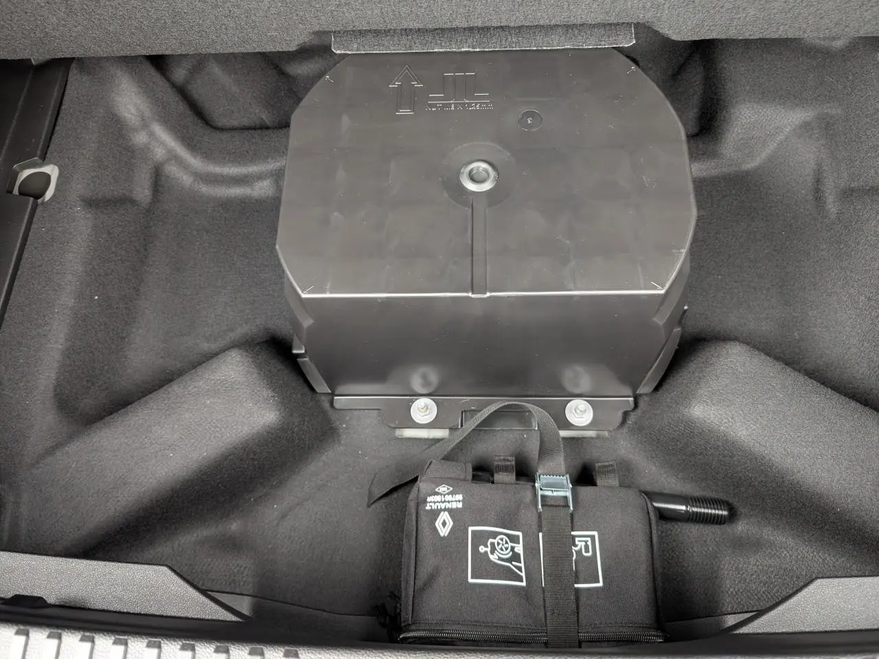 Vue plongeante sur le coffre gris du Renault Austral 2025, montrant le rangement sous plancher avec kit de réparation pneus.