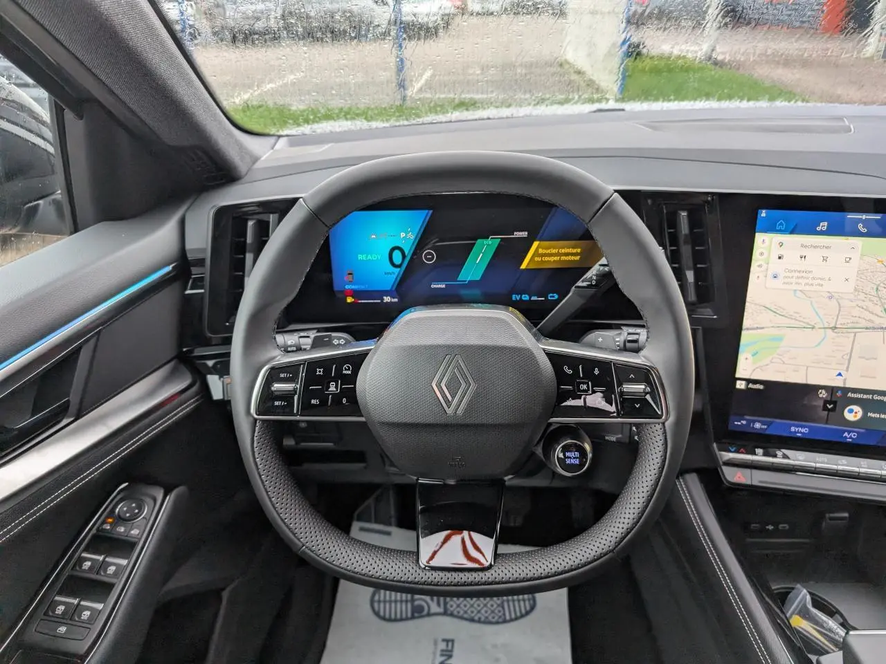 Vue intérieure centrée sur le volant et tableau de bord numérique du Renault Austral gris avec écran tactile latéral.