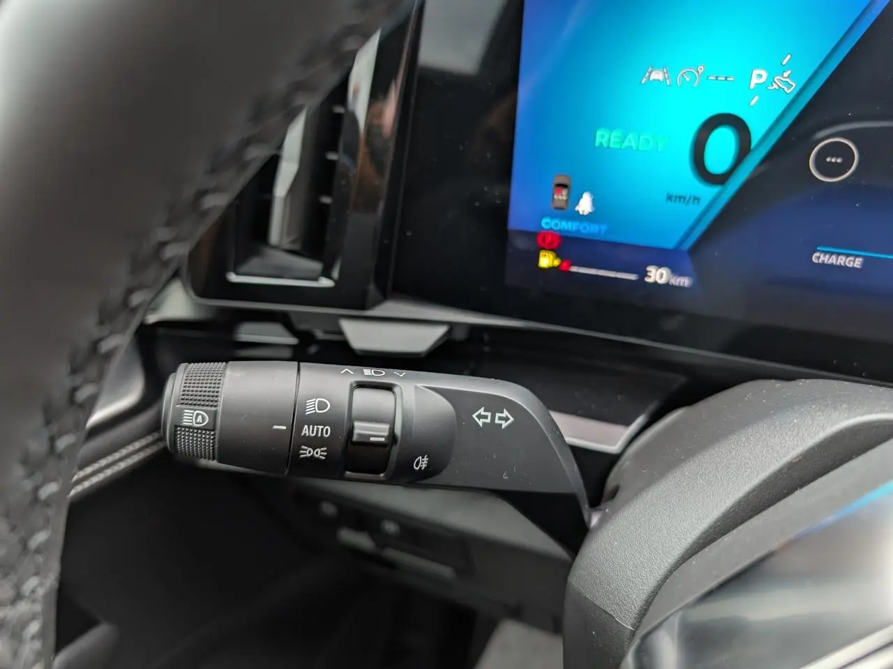 Gros plan sur la commande des feux et clignotants du tableau de bord du Renault Austral 2025, écran digital bleu en arrière-plan.