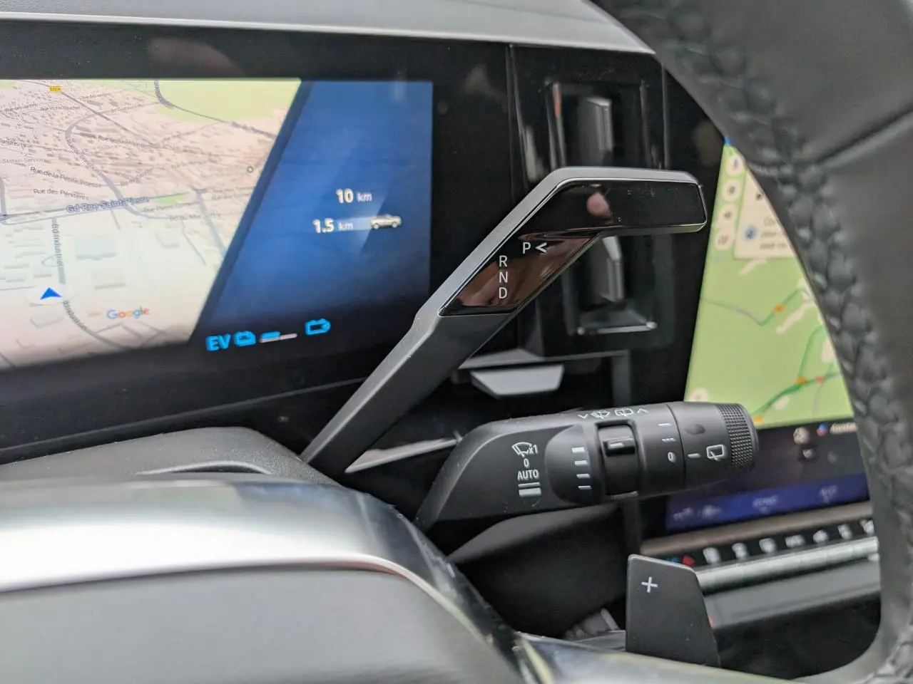 Gros plan sur la commande de boîte automatique et le tableau de bord numérique du Renault Austral gris, vue intérieure côté conducteur.