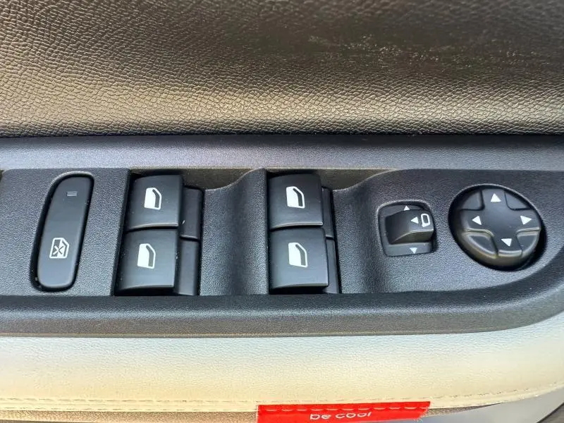 Gros plan sur les commandes des vitres électriques et réglages des rétroviseurs côté conducteur d'une Citroën C3 2025.