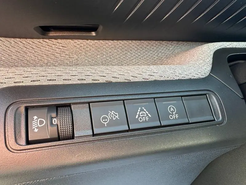 Gros plan sur les commandes de réglage des phares et d'assistance du tableau de bord d'une Citroën C3 2025.