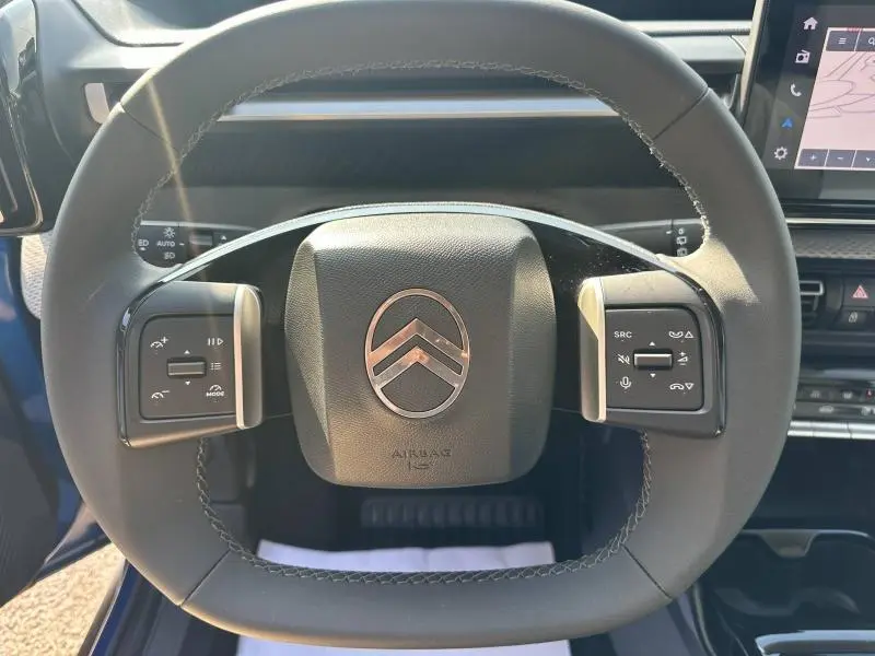 Vue rapprochée du volant noir de la Citroën C3 2025 Bright Blue avec commandes intégrées et logo central chrome.