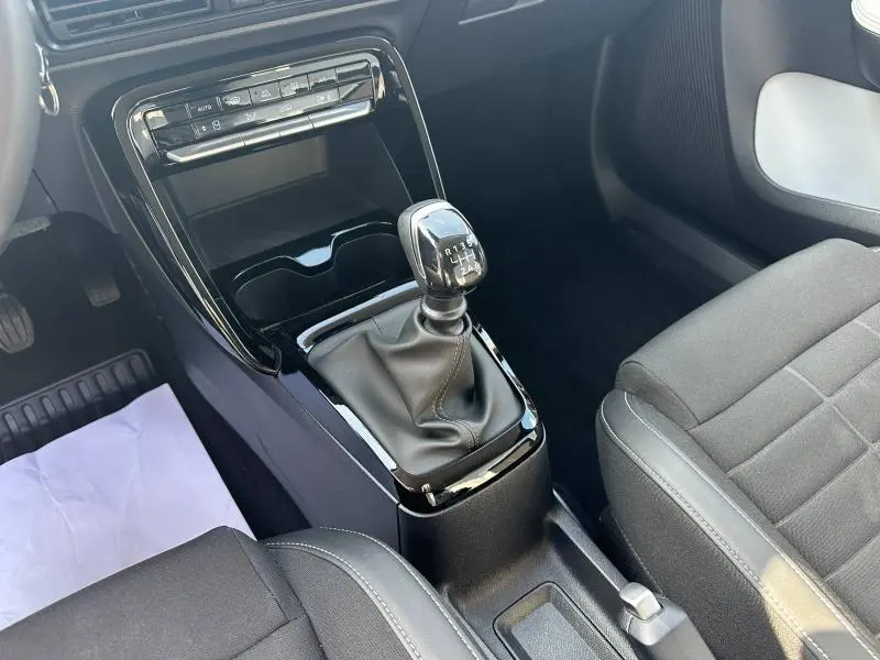 Vue intérieure rapprochée du levier de vitesses manuel noir et des sièges tissu gris de la Citroën C3 1.2 Turbo 2025.
