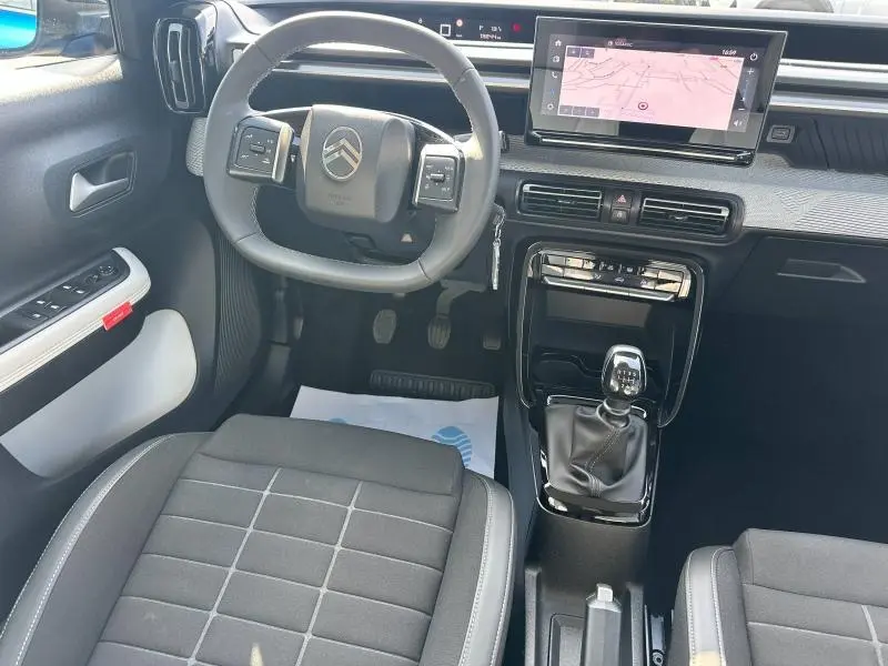 Vue intérieure avant de la Citroën C3 1.2 Turbo 2025, volant multifonctions, écran tactile GPS et levier de vitesse manuel.
