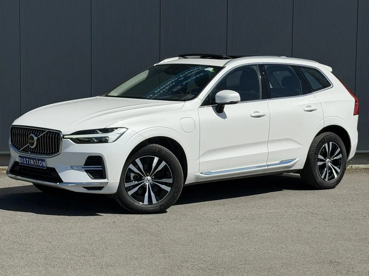 Volvo XC60 T6 AWD PHEV blanc Crystal en 3/4 avant droit, avec jantes alliage et toit ouvrant panoramique.