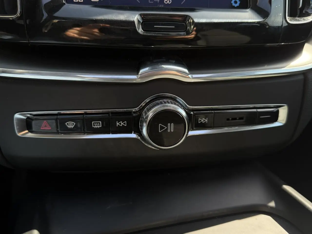 Gros plan sur la commande multimédia centrale chromée du tableau de bord du Volvo XC60 blanc Crystal 2024.