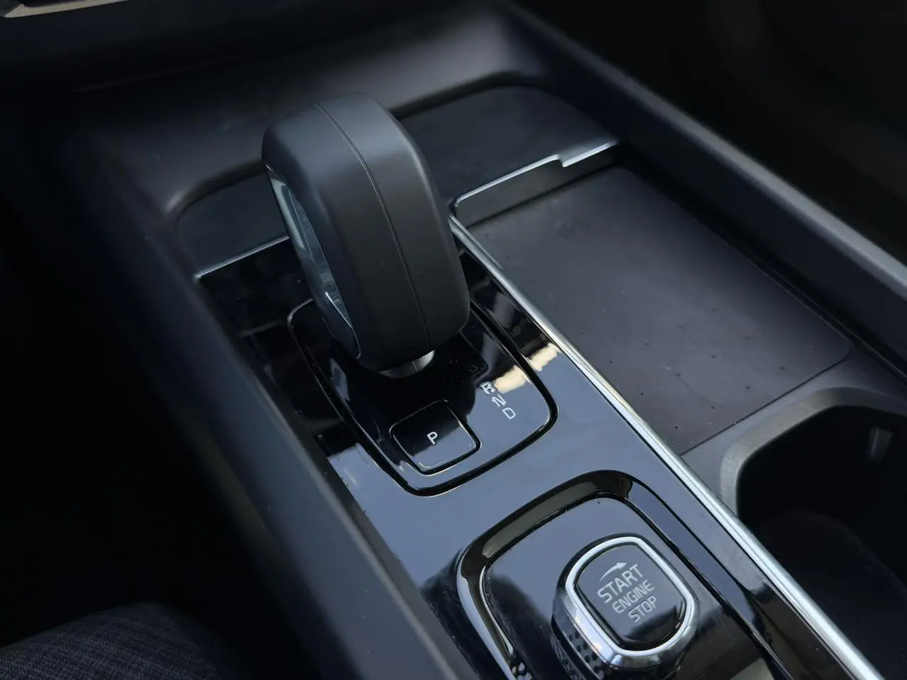 Gros plan sur la console centrale noire du Volvo XC60 2024 avec levier de vitesse automatique et bouton Start/Stop.