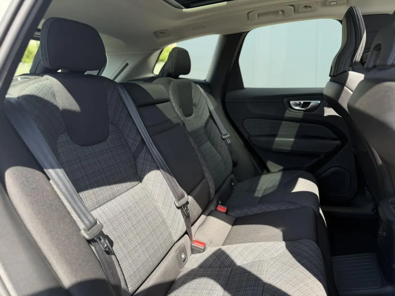 Vue intérieure côté droit des sièges arrière en tissu gris à motifs du Volvo XC60 T6 AWD PHEV 2024.