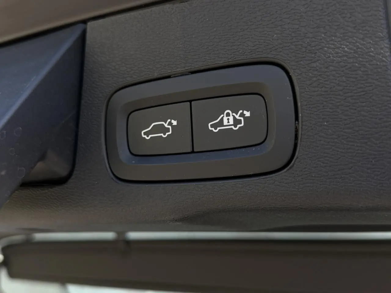 Gros plan sur les boutons de commande du hayon électrique du Volvo XC60 blanc Crystal, intérieur noir.