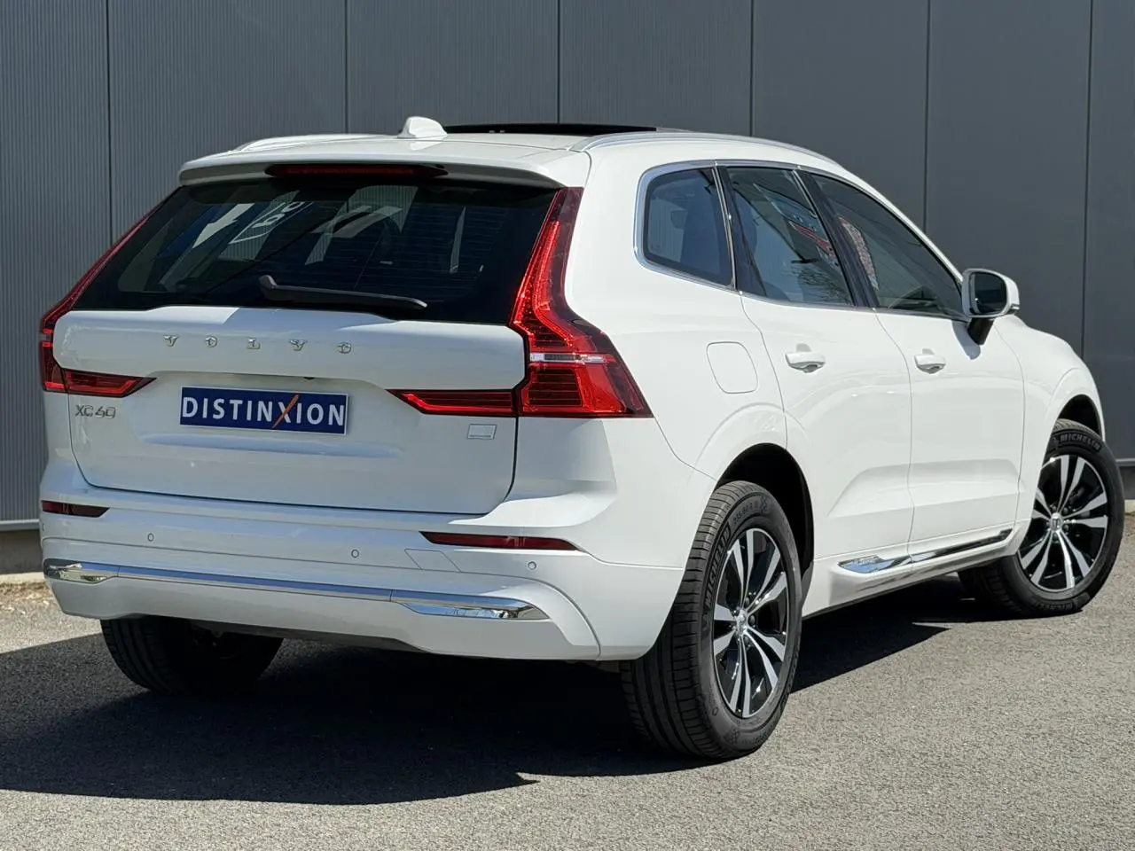 Vue 3/4 arrière droite du Volvo XC60 blanc Crystal avec jantes alliage et contours chromés des vitres.